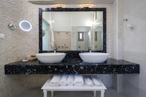 a bathroom with two sinks and a large mirror at Zephyros Hotel in Kamari