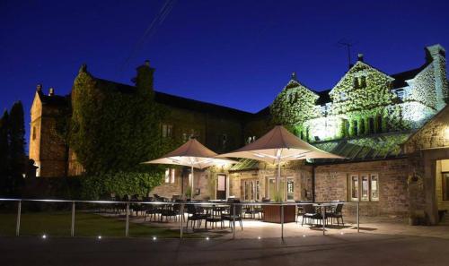 a building with tables and umbrellas in front of it at Stirk House Hotel in Clitheroe