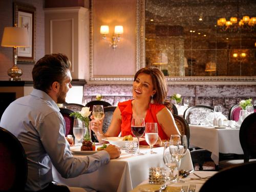 a man and woman sitting at a table with wine glasses at The Rose Hotel in Tralee
