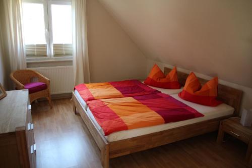 プレローにあるFerienhaus Treibholzのベッドルーム1室(オレンジと赤の枕が付いたベッド1台付)