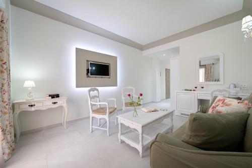 a white living room with a couch and a table at Zephyros Hotel in Kamari