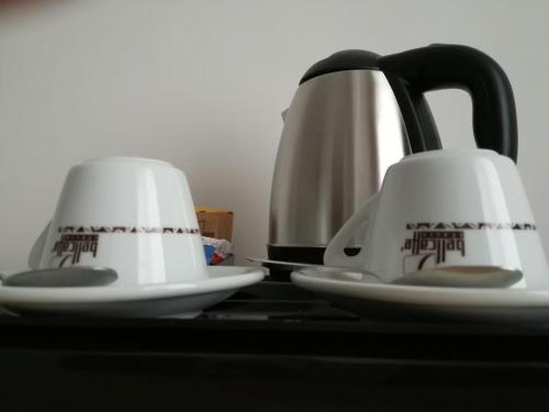 two white cups sitting on top of a table at Hotel Elite Palermo Centro in Palermo