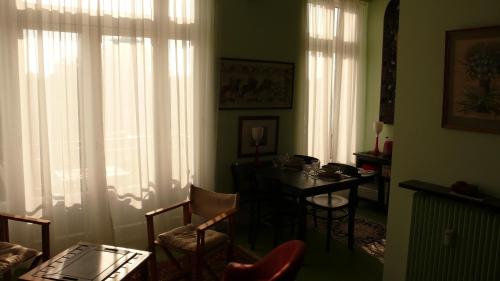 - un salon avec une table, des chaises et des rideaux dans l'établissement Le balcon de l'Hermitage, à Le Touquet-Paris-Plage