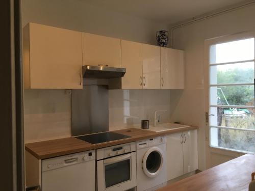 une cuisine avec des armoires blanches et une machine à laver dans l'établissement Villa Pagnol, à Andernos-les-Bains