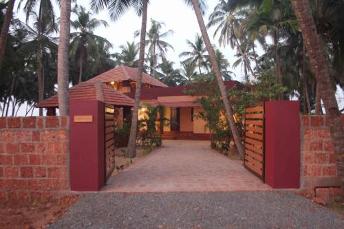 a house with a red gate in front of it at Vretreat in Kokkānisseri