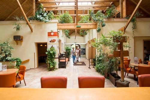 ein Zimmer mit vielen Pflanzen, Tischen und Stühlen in der Unterkunft Gastland M0 Hotel & Conference Center in Szigetszentmiklós