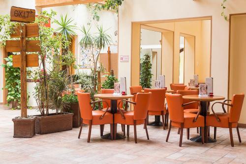 a restaurant with tables and chairs and plants at Gastland M0 Hotel & Conference Center in Szigetszentmiklós