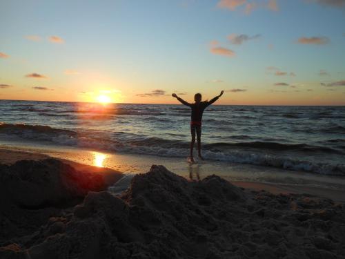 a person standing on the beach watching the sunset at Stilove Wydmy in Sasino