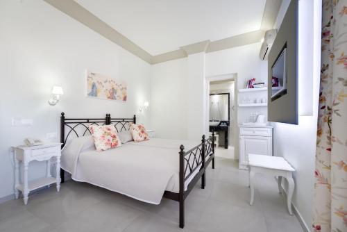 a white bedroom with a bed and a television at Zephyros Hotel in Kamari