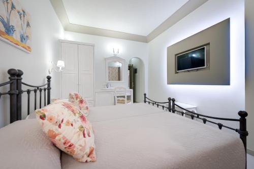 a bedroom with a bed and a tv on the wall at Zephyros Hotel in Kamari