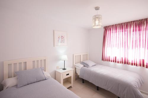 1 dormitorio con 2 camas y una ventana con cortinas rojas en Cardon Big Calm 12, en Costa Calma