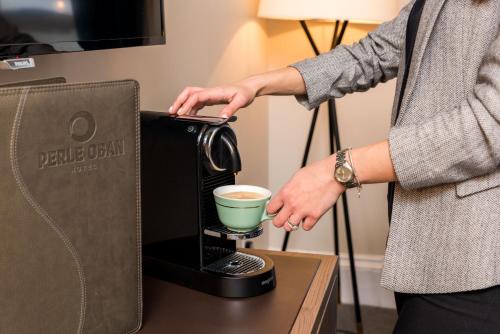 a person is holding a coffee maker on a table at The Perle Oban Hotel & Spa in Oban