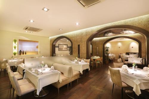 una sala da pranzo con tavoli e sedie bianchi di Abbott Hotel a Navi Mumbai