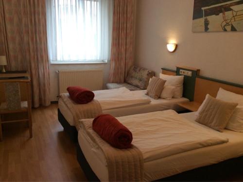 Habitación de hotel con 3 camas con almohadas rojas en Hotel Elsen en Grevenbroich