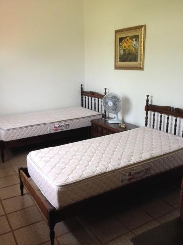 two twin beds in a room with a fan at Morada Guaruja in Palhoça