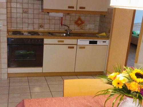 eine Küche mit einem Herd, einer Spüle und einer Vase aus Blumen in der Unterkunft Haus Obertal in Bad Rippoldsau