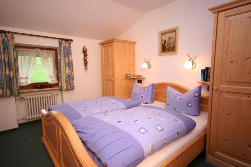 a bedroom with a bed with blue pillows and a window at Landhaus Vogler in Fischen