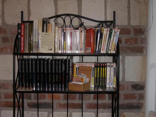 a book shelf filled with books next to a brick wall at Grange de la Herde in Camon