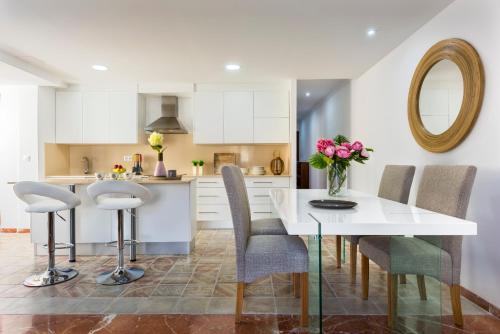 una cocina con una mesa con sillas y un jarrón de flores en Genteel Home Ático Gran Capitán, en Granada