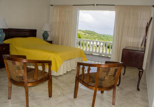 a bedroom with a bed and two chairs and a window at Castles Apartments in Castries