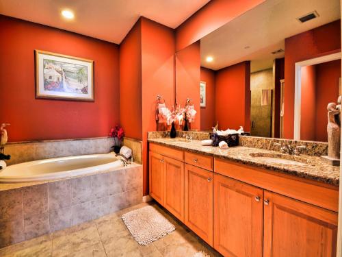 Un baño con paredes naranjas, bañera y lavabo. en Harborview Grande 701, en Clearwater Beach