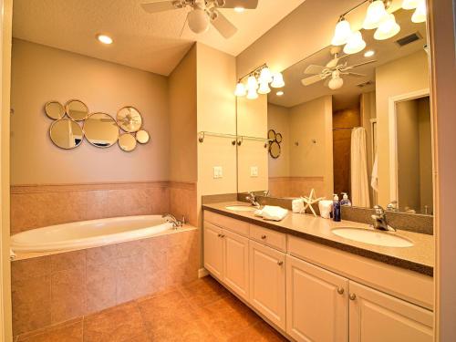 y baño con 2 lavabos, bañera y espejo. en Harborview Grande 802, en Clearwater Beach