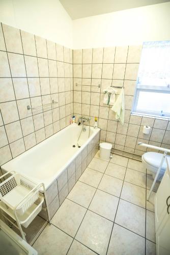a white tiled bathroom with a tub and a sink at Eiði Farmhouse in Grundarfjordur