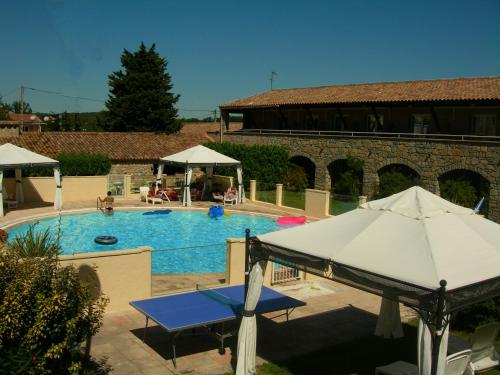 a pool with an umbrella next to a building at Hôtel de la Madeleine à Tornac in Tornac