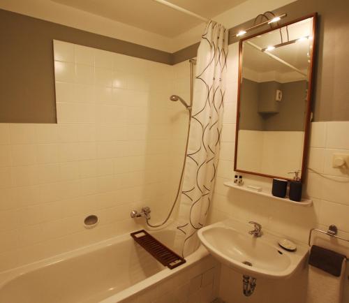 een badkamer met een wastafel, een douche, een bad en een spiegel bij Ferienwohnung am Campus in Oldenburg