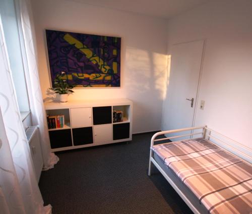 オルデンブルクにあるFerienwohnung am Campusのベッドルーム1室(ベッド2台付)が備わります。壁には絵画が飾られています。