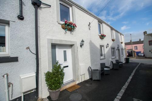 una fila di edifici bianchi con vasi di fiori sopra di Red Rose Cottage a Cockermouth