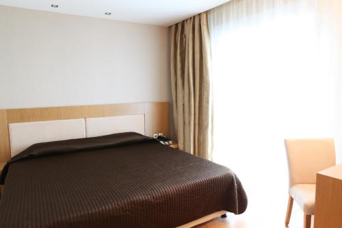 a bedroom with a black bed and a window at Hotel Alfa in Edessa
