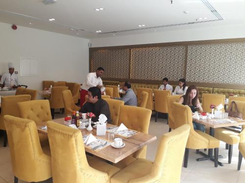 a group of people sitting at tables in a restaurant at Royal Falcon Hotel in Dubai