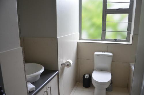 baño con aseo y lavabo y ventana en Be-Still Accommodation, en Swakopmund