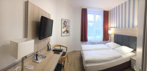 a hotel room with a bed and a desk with a tv at Hotel Hansablick in Berlin