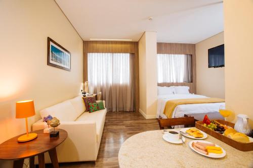 a hotel room with a bed and a living room at Intercity Suape Costa Dourada in Cabo de Santo Agostinho