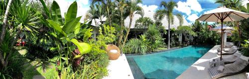 a resort with a swimming pool and palm trees at Hari Indah Boutique Hotel & Spa in Uluwatu