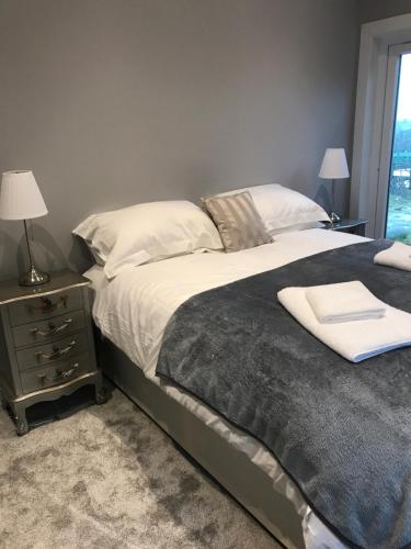 a bedroom with a large bed and a nightstand with a window at Carriage Cottage Hot Tub in Beith