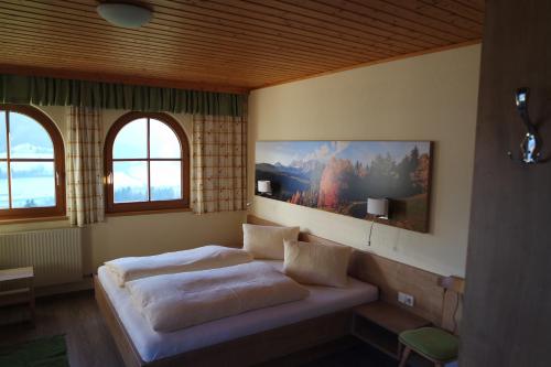 ein Schlafzimmer mit einem Bett und zwei Fenstern in der Unterkunft Gästehaus Davidbauer in Haus im Ennstal