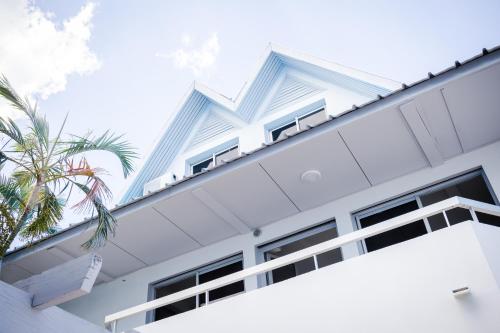 a white building with windows and a palm tree at Hôtel Le Grand Bleu in Saint-Gilles les Bains