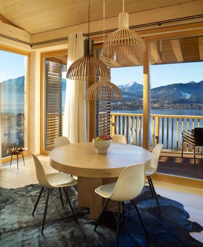 a dining room with a table and chairs and windows at Das Tegernsee in Tegernsee