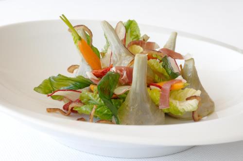 a salad in a white plate on a table at Hôtel Le Bailli De Suffren in Rayol-Canadel-sur-Mer