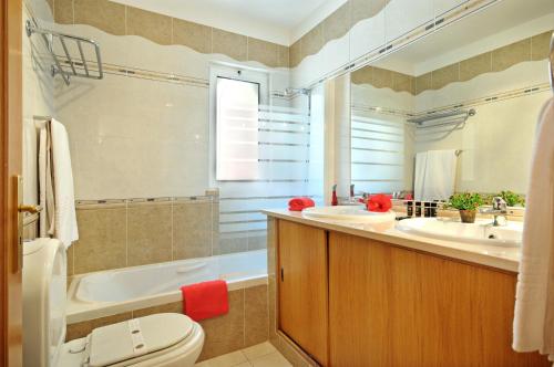 a bathroom with a toilet and a tub and a sink at Jardim da Meia Praia Resort in Lagos