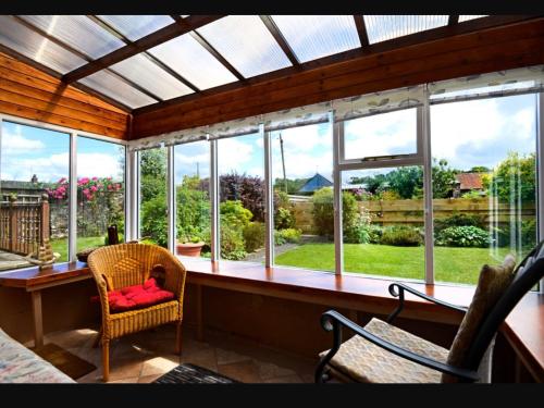 eine abgeschirmte Veranda mit einem Stuhl und einem Fenster in der Unterkunft Granny’s Cottage in Newcastleton