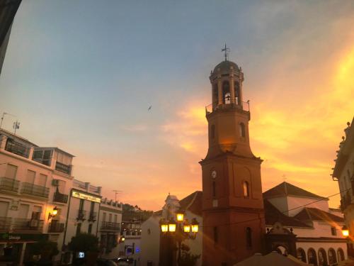 a tall clock tower with a cross on top of it at Salamandra Plaza in Cómpeta