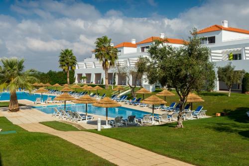 a resort with a swimming pool with chairs and umbrellas at Pateo Village in Albufeira