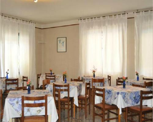 リミニにあるHotel Villa Cavalliのダイニングルーム(テーブル、白いカーテン付きの椅子付)