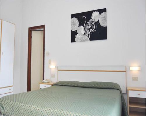 a bedroom with a green bed with a picture on the wall at Hotel Villa Cavalli in Rimini