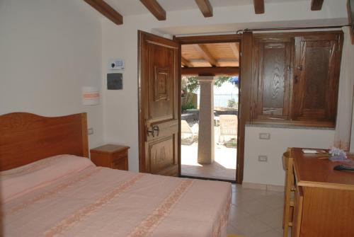 a bedroom with a bed and a door to a yard at Hotel Turismo Rurale Villa Maria Caterina in Cala Gonone