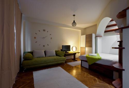 ブダペストにあるGreen Apartmentのソファ付きのベッドルーム1室、壁に時計が備わります。